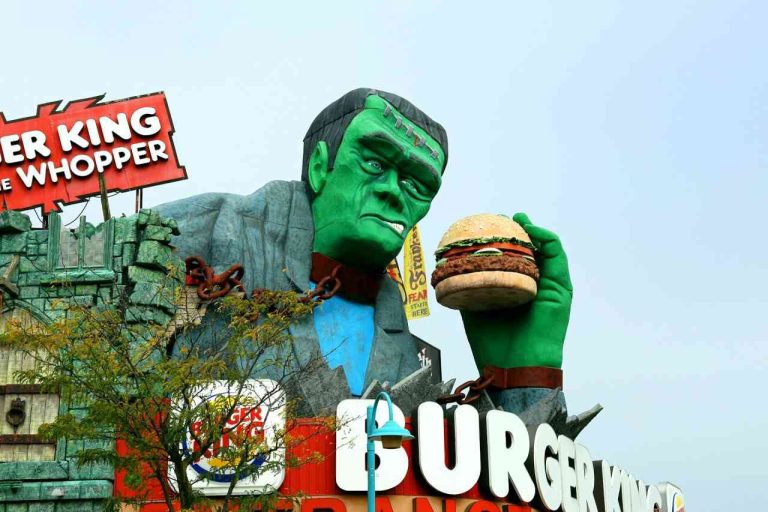 Foto de um grande boneco verde segurando um hambúrguer